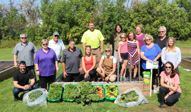 Employees from Raw Materials Company pose for a picture in front of the produce they harvested from the Iron Earth Community Garden in Port Colborne Ontario. 